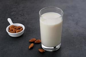 leche de almendras en vaso con almendras sobre mesa de madera. espacio para texto foto