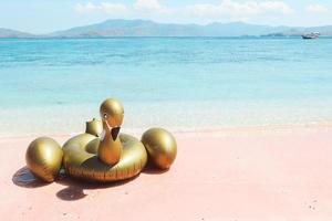 Inflatable swan on pink sand beach photo