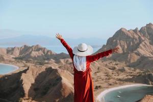 mujer feliz turista con sombrero de verano disfrutando de vacaciones en la cima de la colina foto