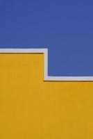 forma geométrica de la pared vacía del edificio de cemento amarillo contra el cielo azul claro en el marco vertical para la arquitectura y el concepto de diseño de fondo foto