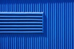 Sunlight on aluminum louver surface of blue warehouse building wall photo