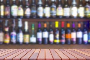 Empty wooden counter with blurred background of many liquor and brandy on shelf of wooden wall decoration in vintage liquor store photo