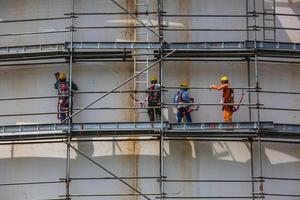 Construction workers tank oil installing scaffolding photo