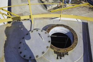 Abrió la alcantarilla oxidada en el espacio confinado del tanque de almacenamiento del techo foto