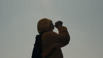 Silhouette of woman closed her eyes, praying on top of a mountain during sunset. Woman with pray and worship god on sunset sky background. video