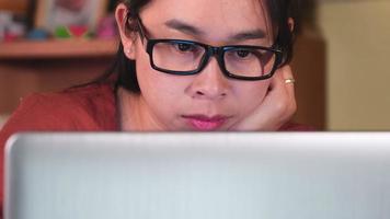 serieuze aziatische vrouw die laptop gebruikt terwijl ze binnenshuis werkt. Aziatische zakenvrouw die serieus nadenkt terwijl ze thuis op haar laptop werkt. video