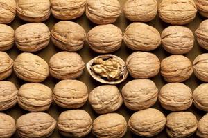 nuez con cáscara, nuez pelada entre otras nueces en una fila uniforme en foto