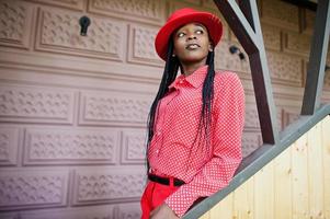 Pretty braids business african american lady bright bossy person friendly wear office red shirt, hat and trousers. photo