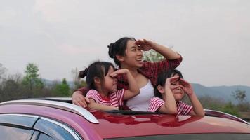 Happy family enjoying road trip on summer vacation. Mother and child enjoying nature along the way in the car on sunroof. Holiday and travel family concept. video