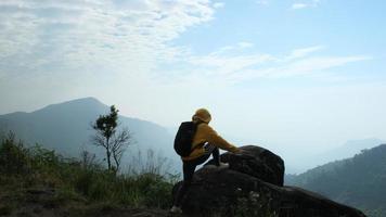 erfolgreiche weibliche wanderer öffnen die arme oben auf dem berg. glückliche Frau, die mit erhobenen Händen auf dem Hintergrund des Sonnenaufgangs zwischen den Bergen steht video