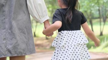 madre sosteniendo la mano de su hija en el jardín de primavera al aire libre. concepto de relación familiar video