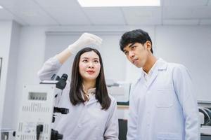 dos jóvenes científicos médicos que miran el tubo de ensayo en el laboratorio médico, seleccionan el enfoque en el científico masculino foto