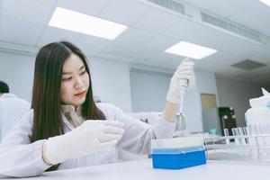 Young medical scientist working in medical laboratory , young female scientist using auto pipette to transfer sample