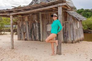 señora de pie fuera de una vieja choza de madera abandonada en praia dos nativos, en trancoso, bahia, brasil foto