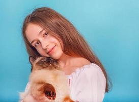 Teen girl with a cat in her arms. Girl on a blue background. photo