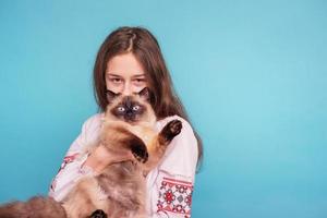 Teen girl with a cat in her arms. Girl on a blue background. Neva masquerade cat. photo