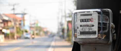 medidor de vatios-hora de electricidad colgado en el poste de cemento al lado de la carretera para monitorear y medir el uso de energía en cada casa en los países asiáticos. foto