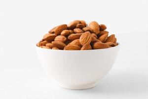 Almond nuts in a white bowl on isolate white background with clipping path, selective focus.front view. photo