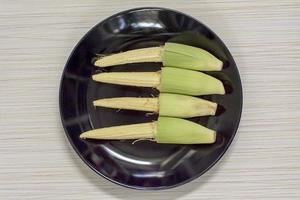 Baby corn in black disk. photo