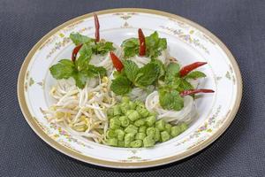 Rice noodles in fish curry sauce with vegetables or  Thai vermicelli eaten with curry is Thai food. The dish is delicious and spicy food. photo