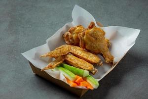 Chicken wings in paper box on a black photo