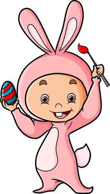 The baby with the rabbit costume is painting the easter egg
