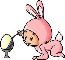 The boy with the rabbit costume is coloring the easter egg vector