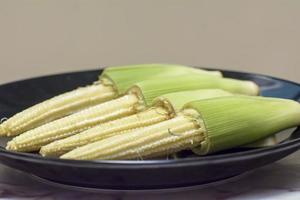 Baby corn in black disk. photo