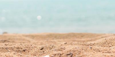 cerrar la superficie de la arena en la playa y desenfocar el primer plano y desenfocar el fondo del mar foto