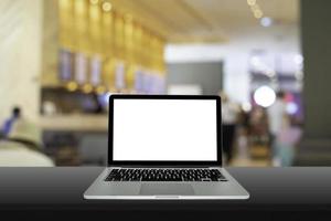 Laptop, computer notebook with blank screen on black wooden with blurred background in the restaurant, warm light tone. photo