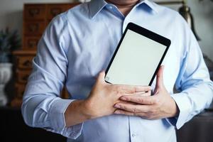 hombre sosteniendo un dispositivo de tableta con una pantalla blanca en blanco para espacio de copia. foto