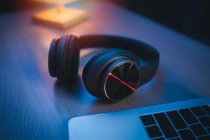 auriculares en la mesa en el estudio de casa para grabar y una computadora portátil usando software de grabación para hacer que la música sea ligera. concepto de producción musical. foto