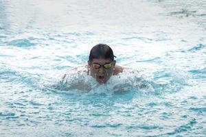 Sport man swimmer in cap breathing performing the swimming breaststroke stroke. Swimmer swimming at the pool. Sport swimming concept. photo