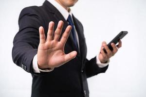 Business man wearing suit and holding mobile phone isolated on white background doing stop signal with palm of the hand. Warning expression with negative and serious. Stop the war signal concept photo