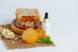 Natural skin care soap and serum with honey and honeycomb laid on white background. photo
