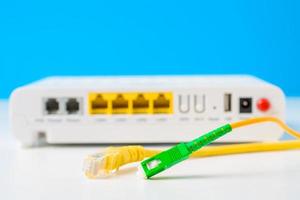 cables de fibra óptica y de red con enrutador inalámbrico de Internet en un fondo azul foto