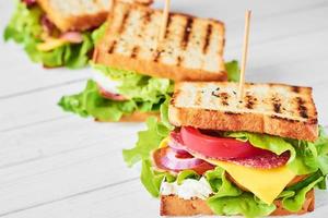 Three sandwiches with ham, lettuce and fresh vegetables on a white background photo