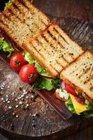 Homemade sandwich with ham, lettuce, cheese and tomato on a wooden background, top view photo