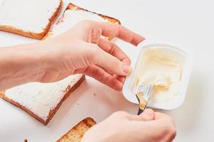 Woman hand make sandwich, spred toasted bread with a cheese photo
