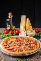 Pizza with ingredients on a wooden background, close up photo