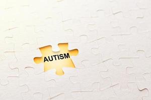 Missing puzzle piece with inscription autism on a yellow background, problem concept photo