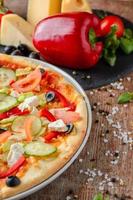 Vegetarian pizza with vegetables and ingredients on a wooden background, close up. Healthy food photo