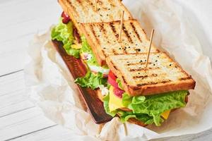 Three sandwiches with ham, lettuce and fresh vegetables on a plate, close up photo