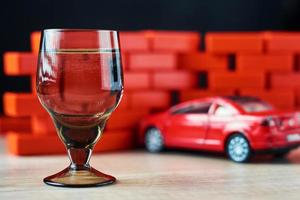 Drunk driving car crash accident. Don't drive after drink concept. Shot glass and a broken car photo