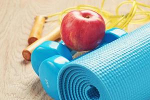 Fitness concept with a blue dumbbells and yoga mat