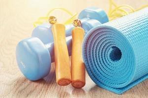 Fitness concept with a blue dumbbells, yoga mat and jump rope photo