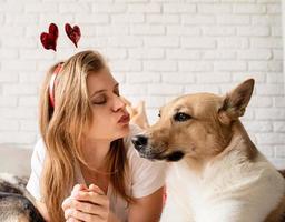 Young woman with her cute shepherd at home having fun and kissing photo