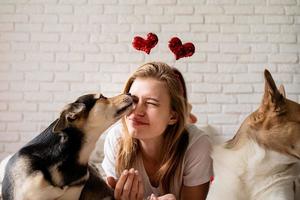 Young woman with her cute shepherd at home having fun and kissing photo