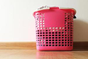 Basket with dirty laundry on the wooden floor in room. photo