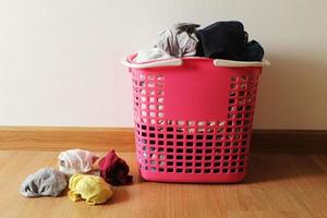Basket with dirty laundry on the wooden floor in room.